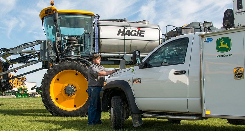 man with Hagie sprayer and John Deere truck